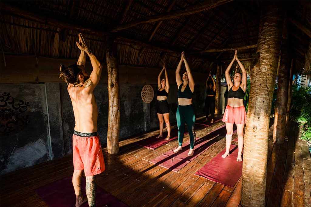 A group of yogis practice at sunset together in Alive Beach House's tropical outdoor yoga studio in Nicaragua