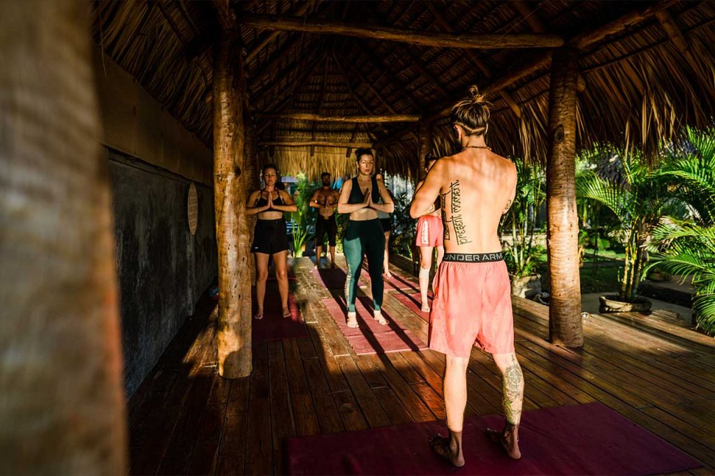 Yogis practice at sunset together in Alive Beach House's tropical outdoor yoga studio in Nicaragua