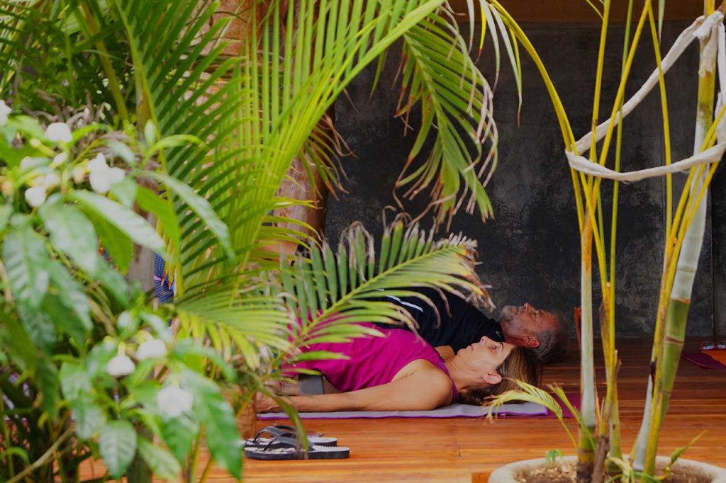 A couple takes a yoga class in Alive Beach House hotel's tropical outdoor yoga studio in Nicaragua
