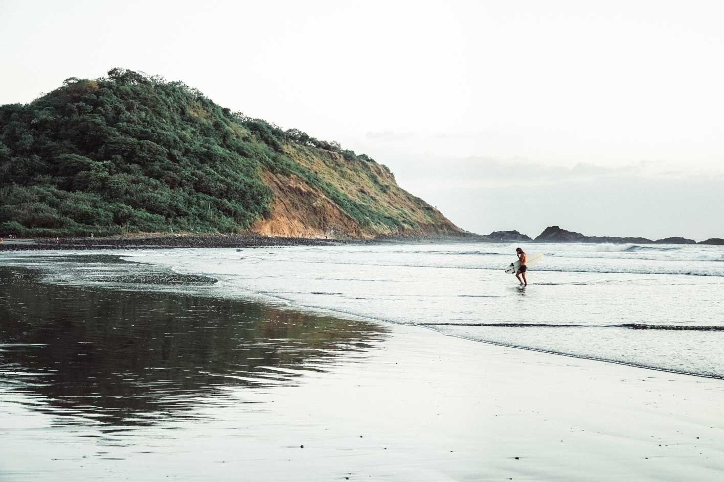 A single surfer emerges from the waves outside of Alive Beach House hotel in El Transito Nicaragua